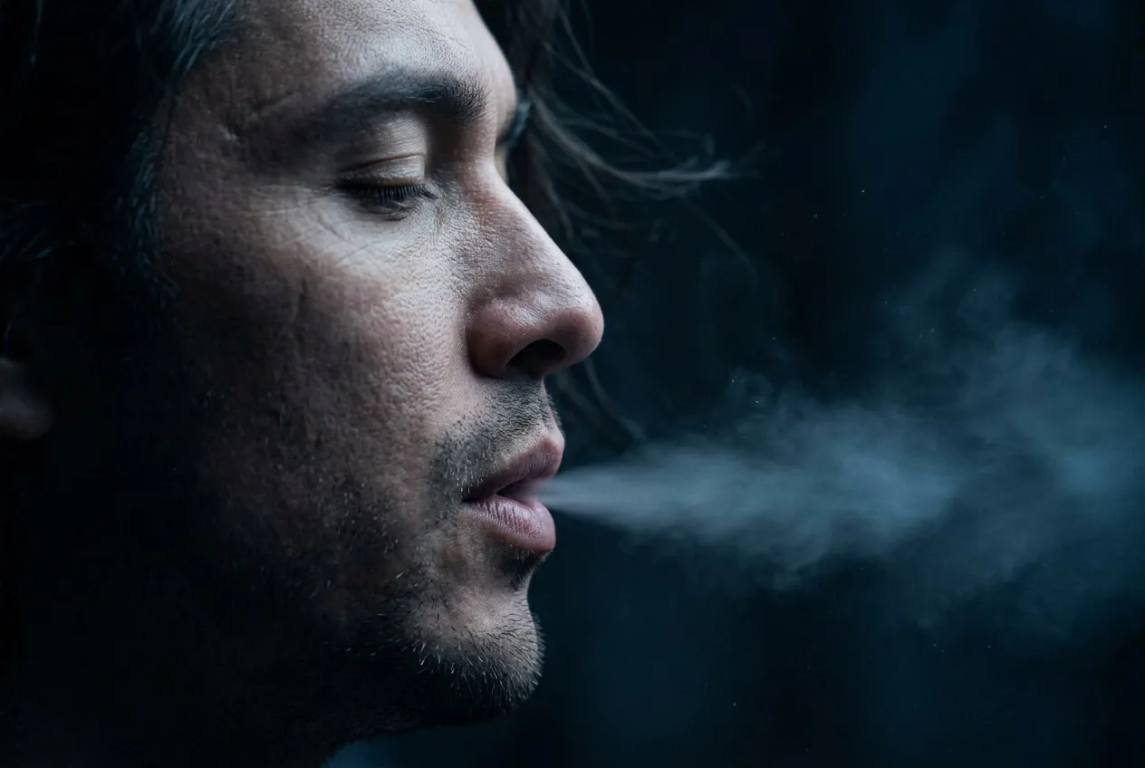 側臉極近特寫,閉眼微張口緩緩吐氣,呼吸化為銀藍色光霧溶入黑暗空氣中