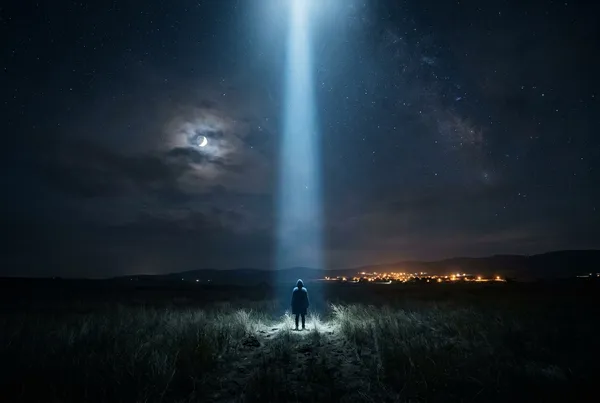 孤身人影站在月光下的曠野中心，一道垂直光柱從天而降，遠方隱約可見城鎮燈火