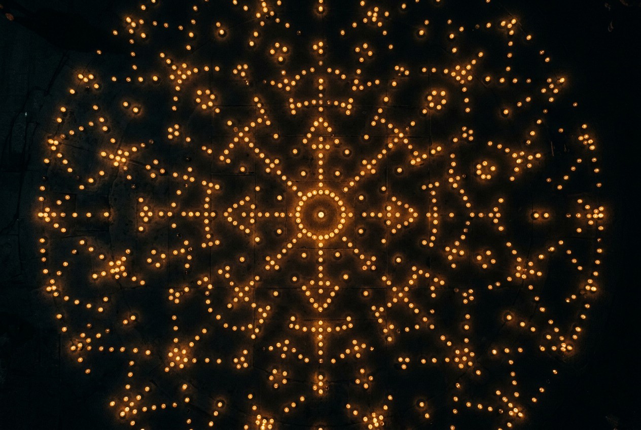 俯瞰視角，數百點燭火散落黑暗大地，集體光點隱約構成星座曼陀羅圖形，象徵個體覺醒匯聚成集體轉化